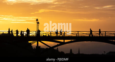 Silhouetted people crossing a bridge at sunset in Paris Stock Photo - Alamy
