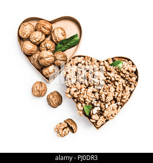 Walnut kernels in heart shaped box, whole walnuts and nutshells as healthy eating and alternative medicine concept, objects isolated on white backgrou Stock Photo
