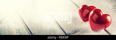 Two red hearts on wooden table. Romantic panoramatic banner for valetines or wedding day. Stock Photo