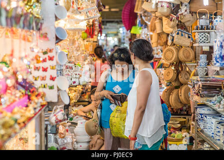 Ho Chi Minh City, Vietnam - April 27, 2018: two woman travelers buy souvenirs in a shop in Ben Thanh Market, one of them checks money in her wallet. Stock Photo