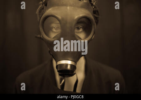Unrecognizable young woman in scary gas mask looking at camera while standing on dark background Stock Photo