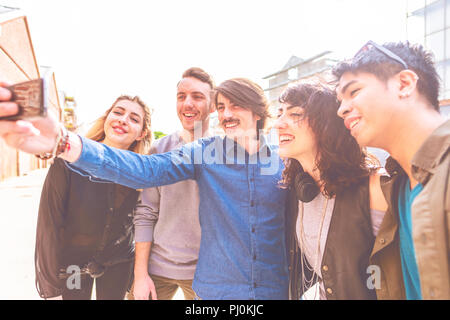 group of friends millennials outdoor using smart phone taking selfie - internet, social network, happiness concept Stock Photo
