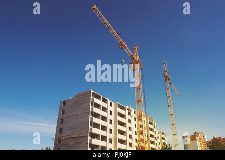 Picture of a building under construction in the city. tower crane and unfinished building against the blue sky. Stock Photo