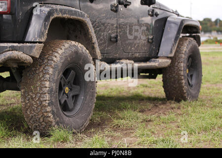 Copenhagen, Denmark – September 1, 2018: Close up of dirty Jeep Wrangler after driving heavy off-road in wet terrain. Wheels soiled in mud and dirt. S Stock Photo