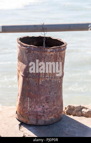 A Close up view of a rusted metal bucket with a wire handle attached to the railing Stock Photo