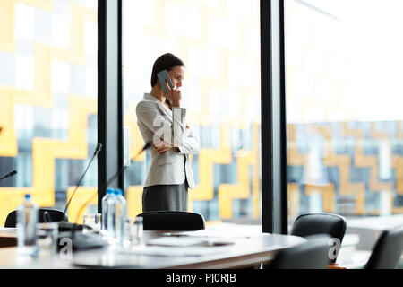 Businesswoman Speaking by Phone in Office Stock Photo