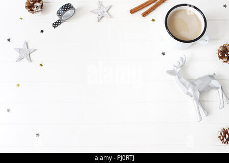 Christmas composition. Hot chocolate, pine cones, cinnamon sticks, stars confetti and reindeer on white table background. Creative winter holiday concept. Flat lay, top view Stock Photo