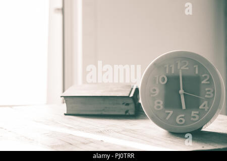 green alarm clock on table, light enters house, blur old book on table, image vintage and retro, Stock Photo