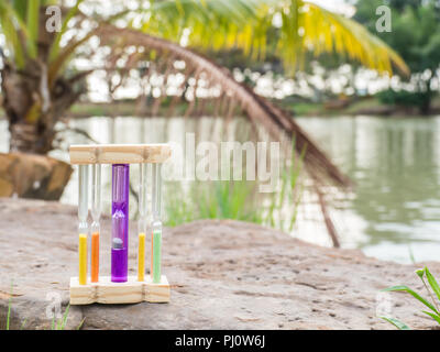 Hourglass on stone and blurred lake background, Stock Photo