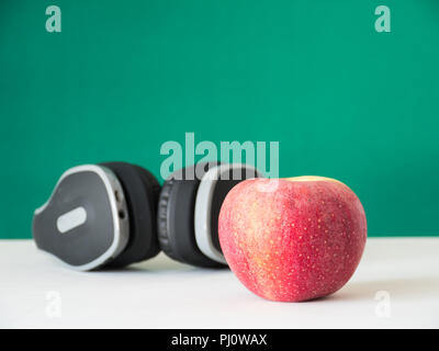 Red Apple and earphone on green background, Stock Photo