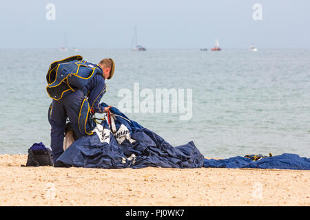 Member of the Tigers Freefall Parachute Team collecting up parachute after descending onto Bournemouth beach for the Bournemouth Air Festival, August Stock Photo