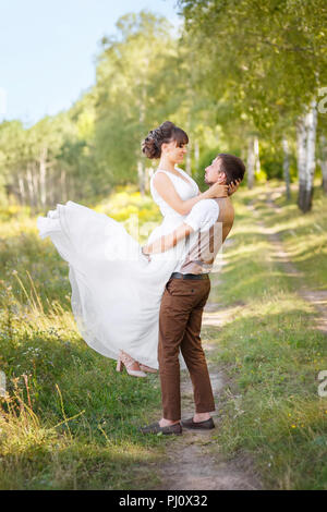 groom holding bride on hands outdoors Stock Photo