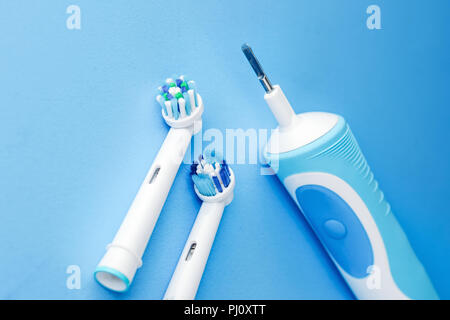 Modern electric toothbrush and spare heads on blue background, close up Stock Photo