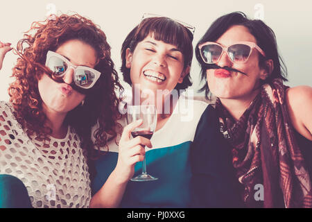 three caucasian females friends stay together in friendship and craziness using hair like moustache and happiness relationship concept. vintage full c Stock Photo