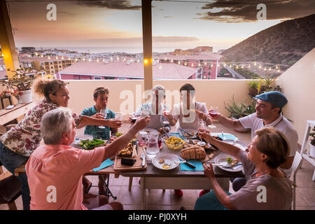 group of friends and parents at home dining together and clinking glasses with beverages. everybody smile and have fun celebrating in friendship. happ Stock Photo