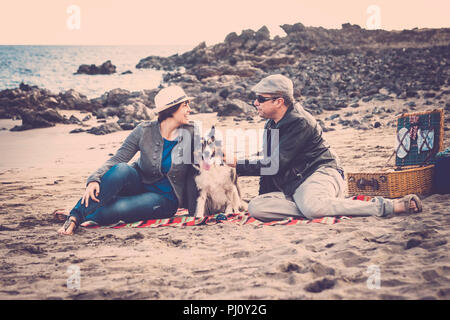 nice group of dog, man and woman young people having fun together at the beach doing picnic and enjoying the outdoor leisure activity. fashion people  Stock Photo