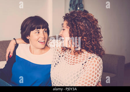 nice time and happiness with laugh and smiles for two caucasian friends lay down together on the sofa at home. friendship concept for indoor picture w Stock Photo