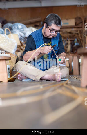 Ichiro Iwao splits strips of bamboo to make baskets at Iwao Chikuran's workshop in Beppu City, Oita Prefecture, Japan on Sept. 20. 2016. Beppu is amon Stock Photo