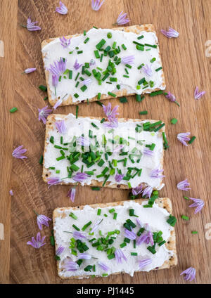Dairy and lactose-free vegan cream cheese spread made from cashew and macadamia nuts on crackers with fresh chopped chives and edible chive flowers on Stock Photo