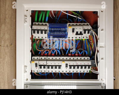 Close up of white frame panel electrical switch board, with colourful cables automatic circuit switchers breakers and fuses Stock Photo