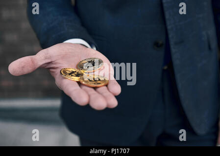 Gold coins bitcoin stacked in the palms hands of a young woman on a dark background close-up. Crypto currency. Anonymous Stock Photo