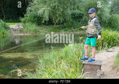 Nine year old boy trout fishing at Church Paddock Trout Fishery, Winchester, United Kingdom. Stock Photo
