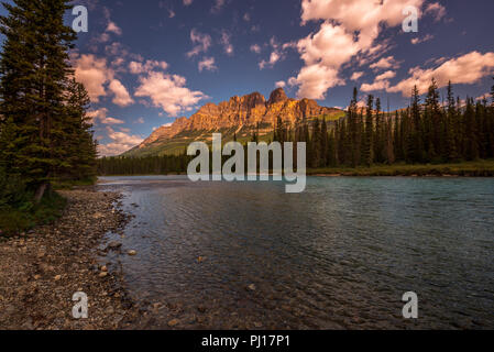 Castle mountain reflects a golden glow against a dramatic blue sky background. Stock Photo