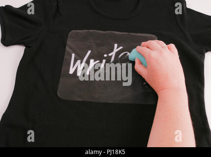 Black T Shirt with writing being wiped off by hand with cloth, word Write Stock Photo