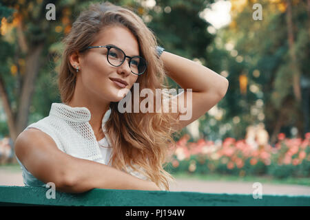 Pretty woman with beautiful hair and glasses enjoying a good day. while looking  Positive woman having a break from city noise and work breathing fres Stock Photo