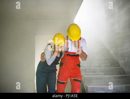 Woman and man workers suffocating at the construction site. Stock Photo