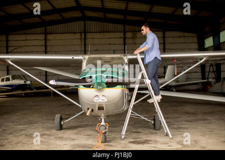 Handsome young pilot checking airplane  in the hangar Stock Photo