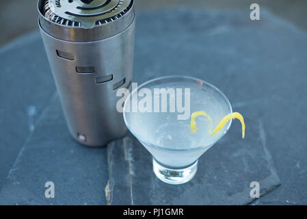 A refreshing shaker-made vodka martini with a lemon twist made on a warm summer evening during a party with friends and family Stock Photo