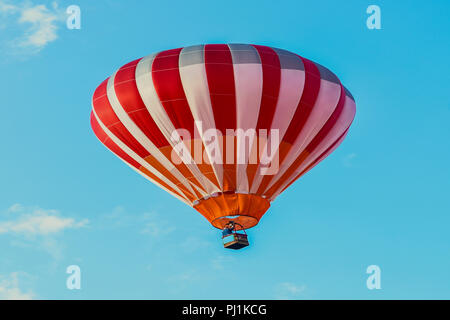 Red and white hot air balloon rising in air. Stock Photo