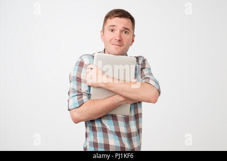 Portrait of confident young man laptop standing against blue wall Stock Photo