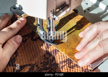 tailor sews leather pieces on sewing machine close up Stock Photo