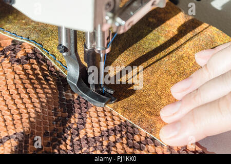 designer sews leather pieces on sewing machine close up Stock Photo
