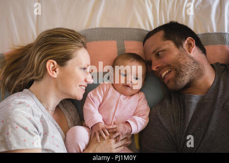 Parents lying with baby on bed in bedroom Stock Photo