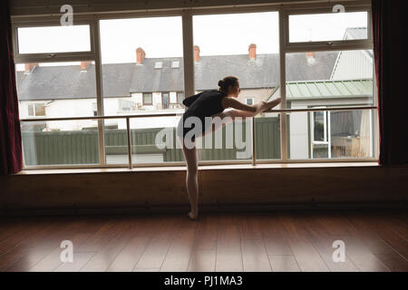 Ballerina stretching on barre while practicing ballet dance Stock Photo