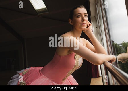 Ballerina looking through window in dance studio Stock Photo