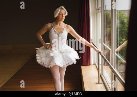 Ballerina looking through window in dance studio Stock Photo