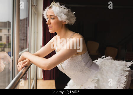 Ballerina looking through window in dance studio Stock Photo