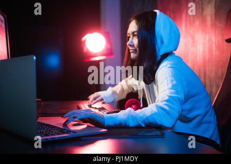 young hooded female hacker developing malware Stock Photo