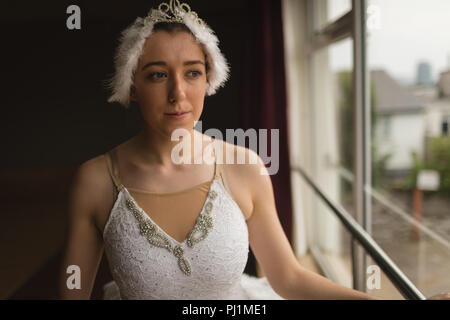 Ballerina looking through window in dance studio Stock Photo