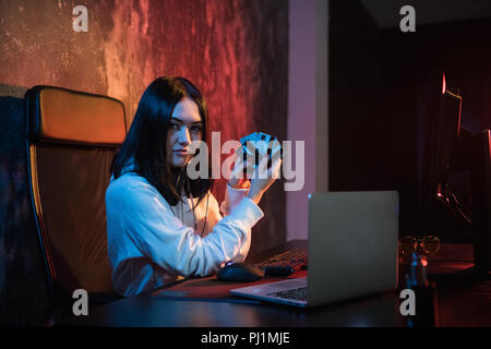 Closeup of young female theift in sweatshirt with hood transfering money from bills of stolen creding cards Stock Photo