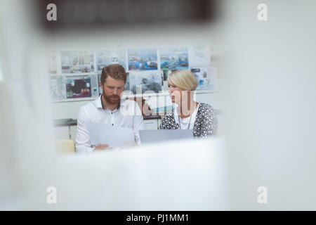 Executives discussing over document at desk Stock Photo