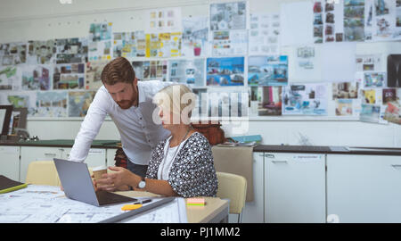 Executives discussing over tablet at desk Stock Photo