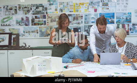 Executives discussing over tablet at desk Stock Photo