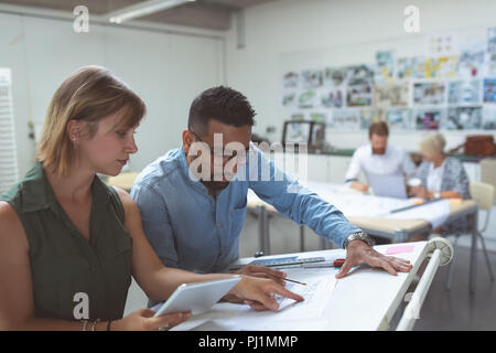 Executives discussing over blueprint on drafting table Stock Photo
