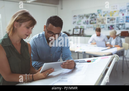 Executives discussing over digital tablet on drafting table Stock Photo
