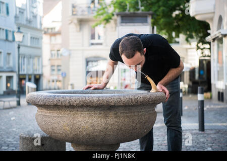 Caucasian young man preparing to drinking water from the fountain. Stock Photo